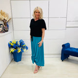 Woman in black top and blue skirt standing in a room with decorative elements.