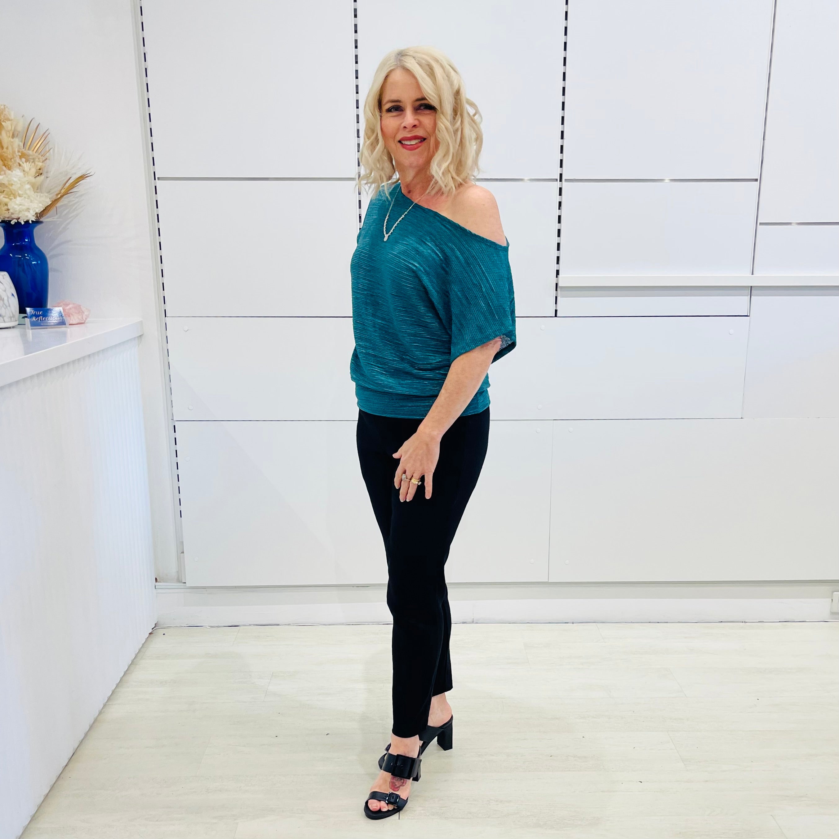Stunning off the shoulder emerald green top with delicate shimmer. Flattering relaxed fit cut with stretch waistband for style and fit. Worn with black tailored pants.