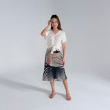 Woman wearing a white top and patterned skirt on a plain background