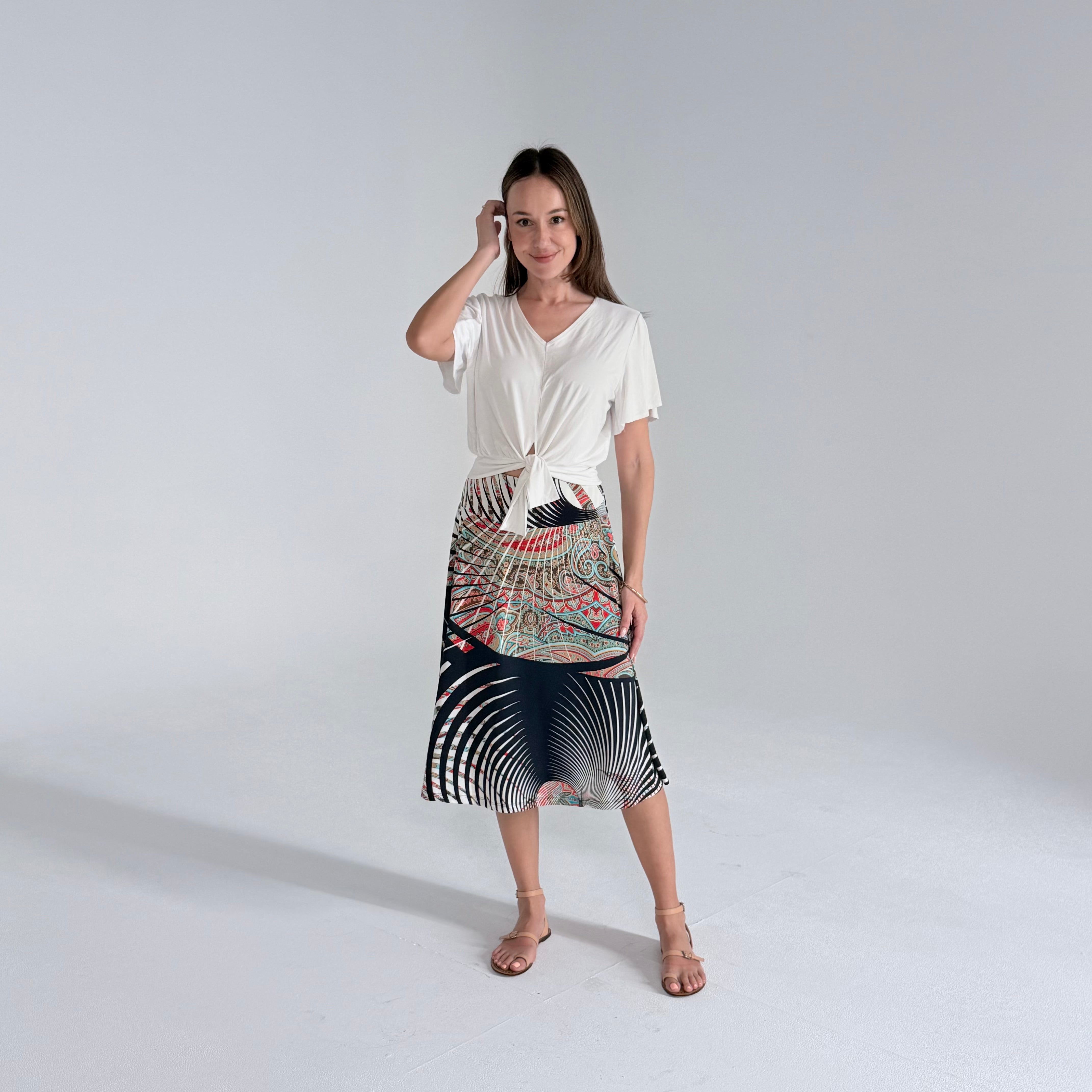 Woman wearing a white top and patterned skirt on a plain background