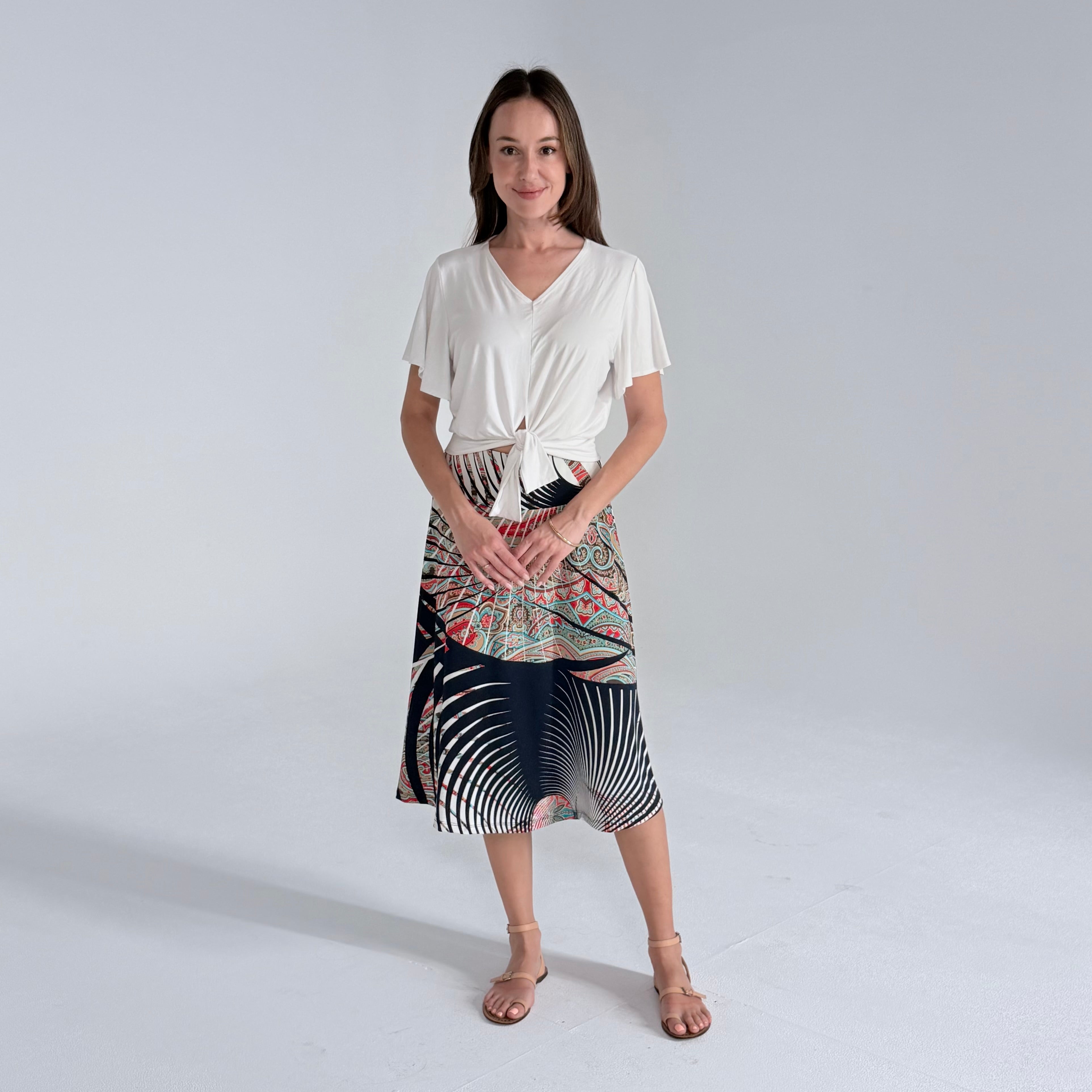 Woman wearing a white top and patterned skirt on a plain background