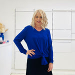 Relaxed fit, cobalt blue bamboo, v neckline, long sleeve, tie front detail, dressy top. Worn with midi length skirt with slight hemline ruffle in black.