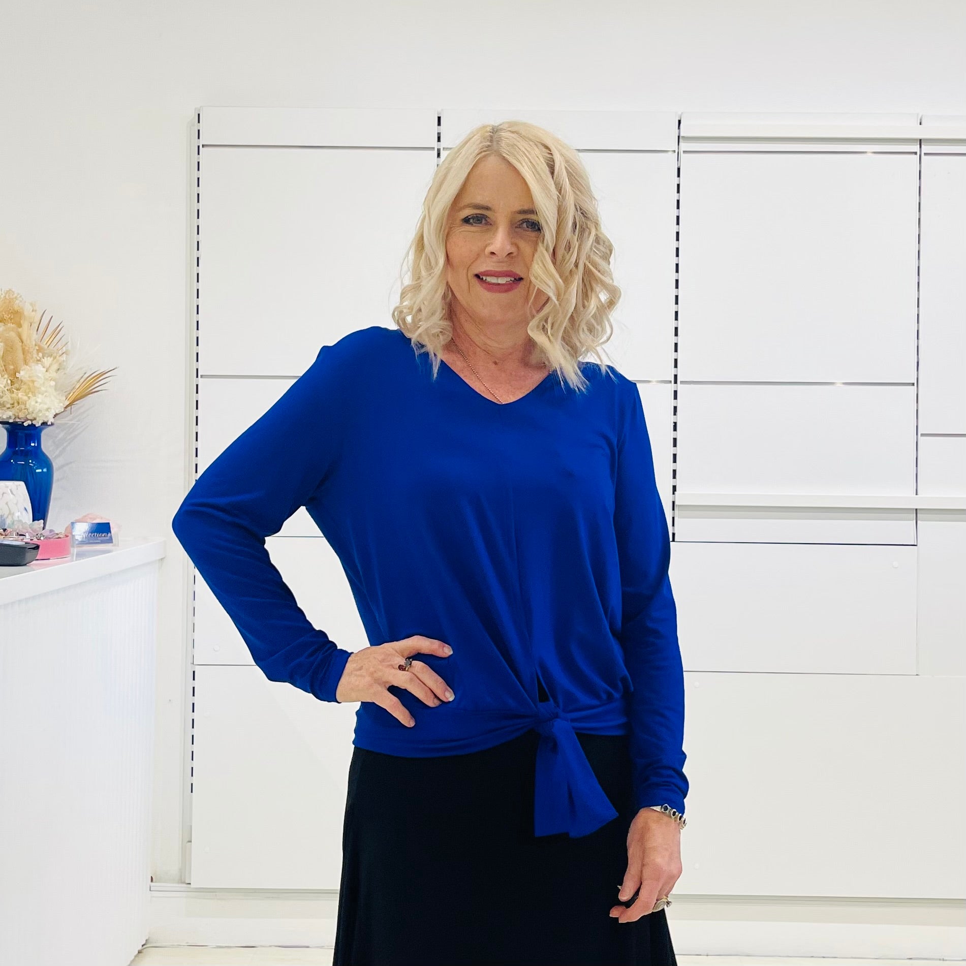 Relaxed fit, cobalt blue bamboo, v neckline, long sleeve, tie front detail, dressy top. Worn with midi length skirt with slight hemline ruffle in black.