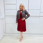 Woman wearing the Penelope dress n rich ruby red, featuring a fit-and-flare, knee length, slihouette, full length sleeves, and a cut out neckline. With embroidered silk bolero Selena Jacket.