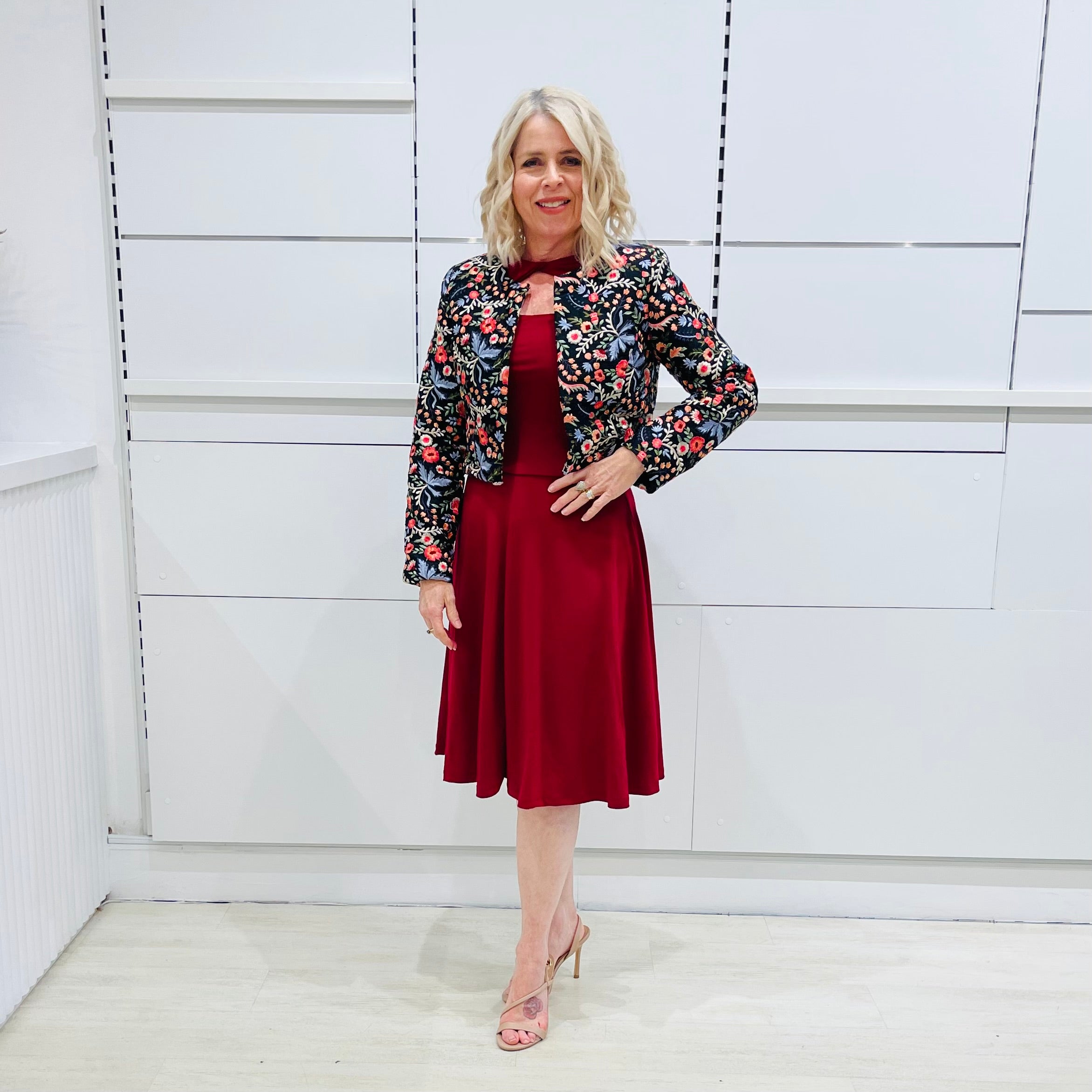 Woman wearing the Penelope dress n rich ruby red, featuring a fit-and-flare, knee length, slihouette, full length sleeves, and a cut out neckline. With embroidered silk bolero Selena Jacket.