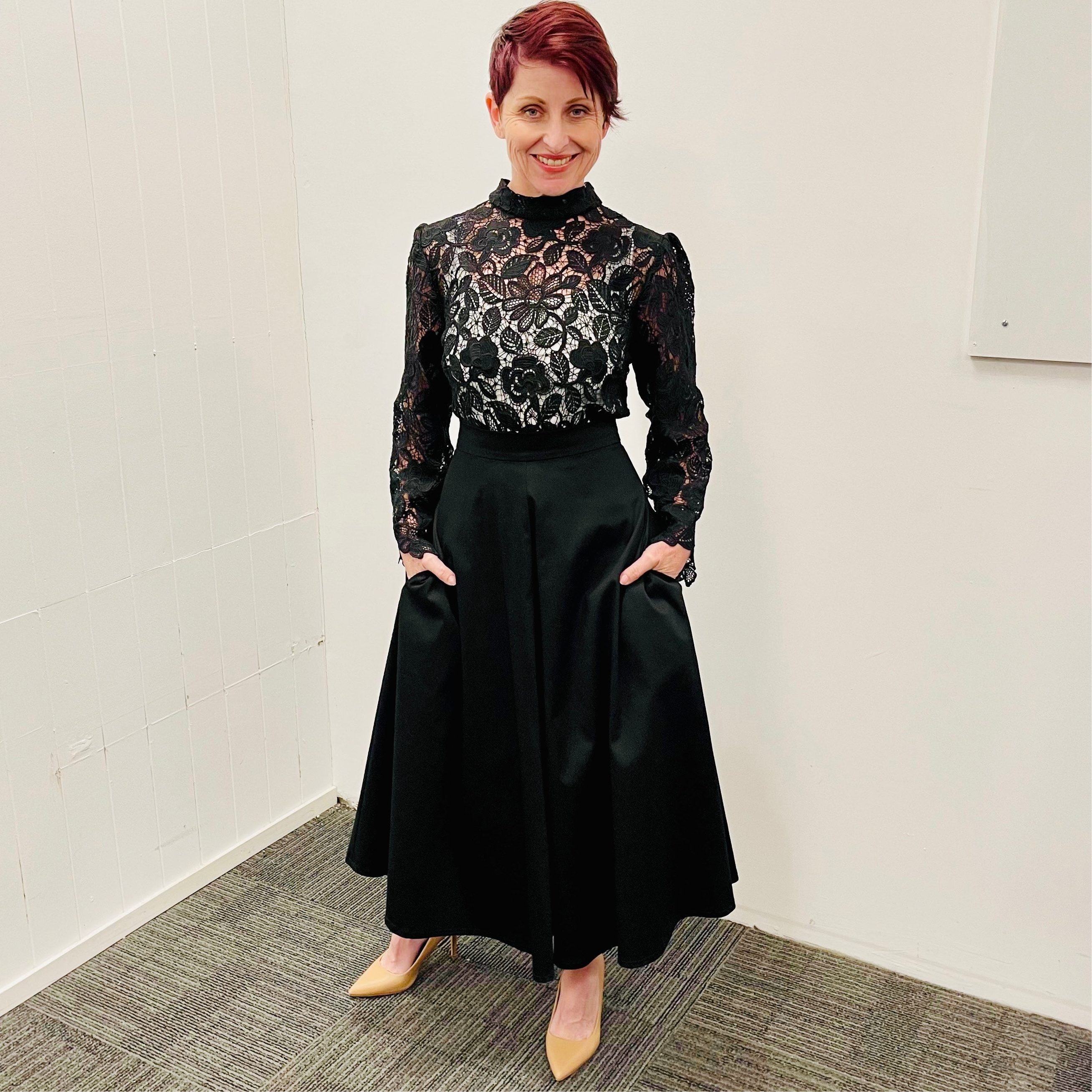 Black, cotton sateen, paneled, midi length, a line skirt, with high waistband and pockets. Worn with black sheer lace, high neckline , long sleeve blouse.