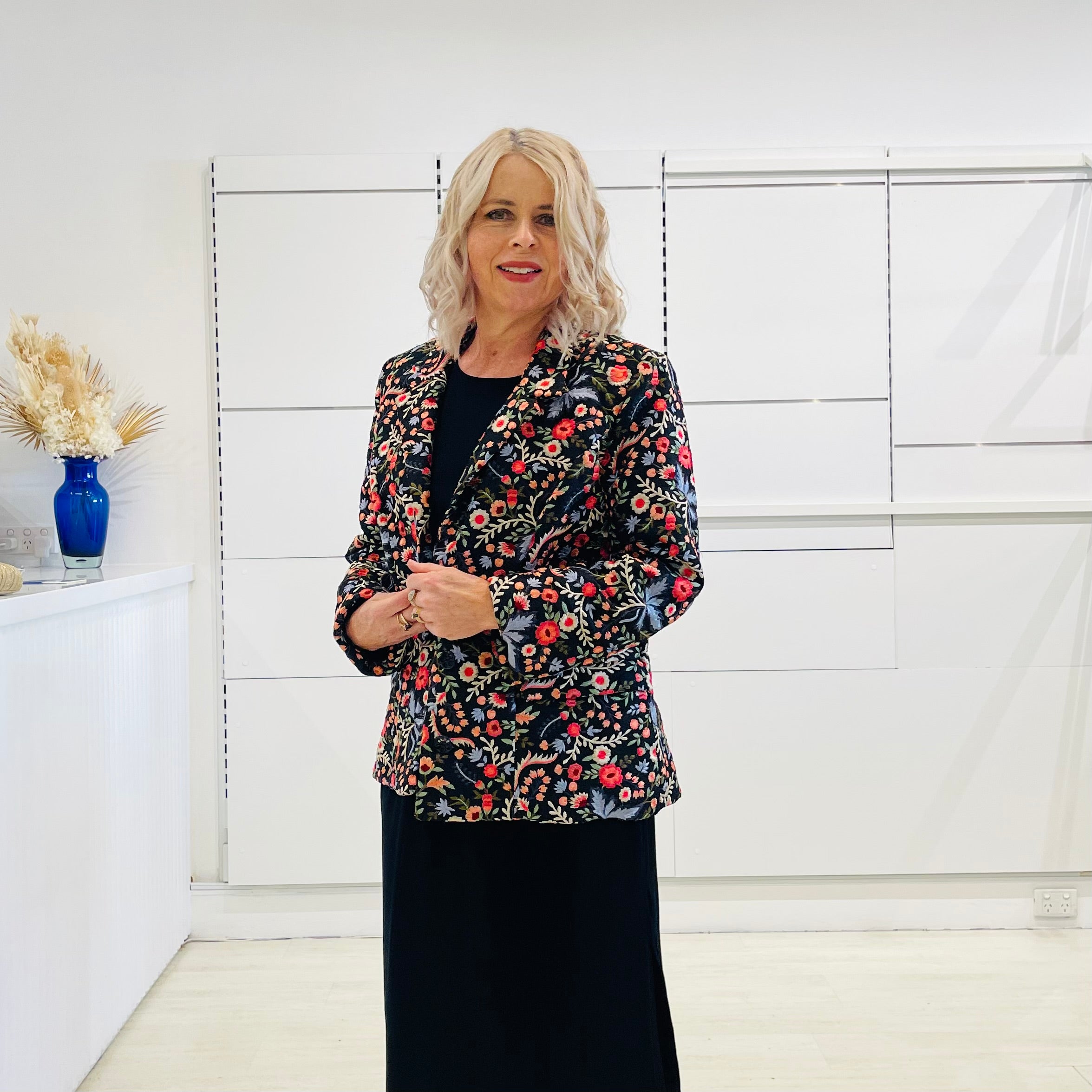 Black silk, with floral embroidery, collar, lapels, 3 button front closure, with pockets jacket. Worn with dressy straight black dress with side seam splits.