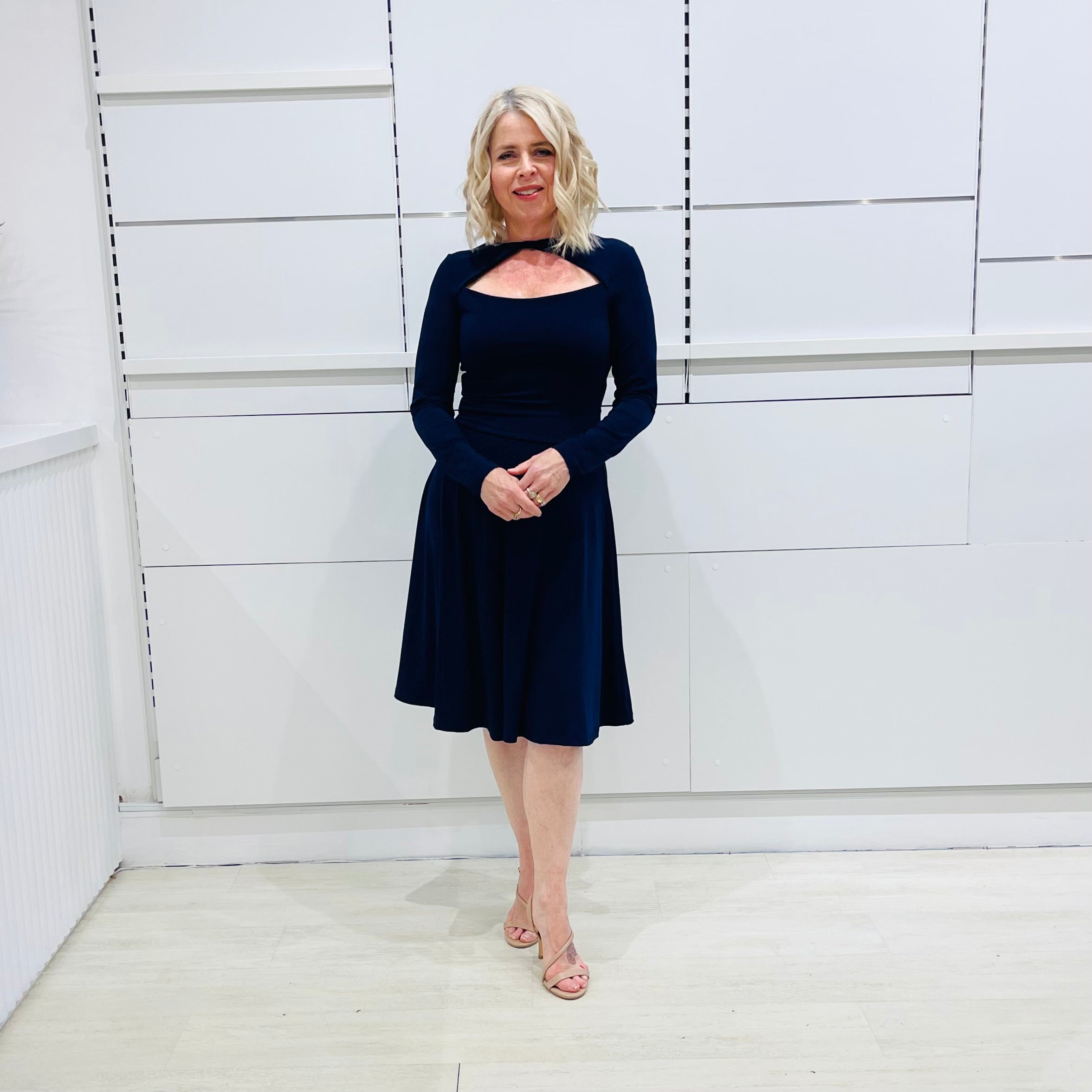 Penelope dress in deep navy blue, worn by model- elegant long sleeve design, knee length, with modern neckline.