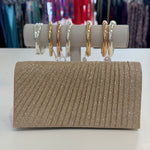 Sparkly clutch bag on a white surface with jewelry in the background