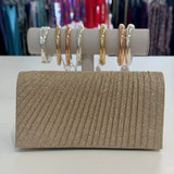 Sparkly clutch bag on a white surface with jewelry in the background