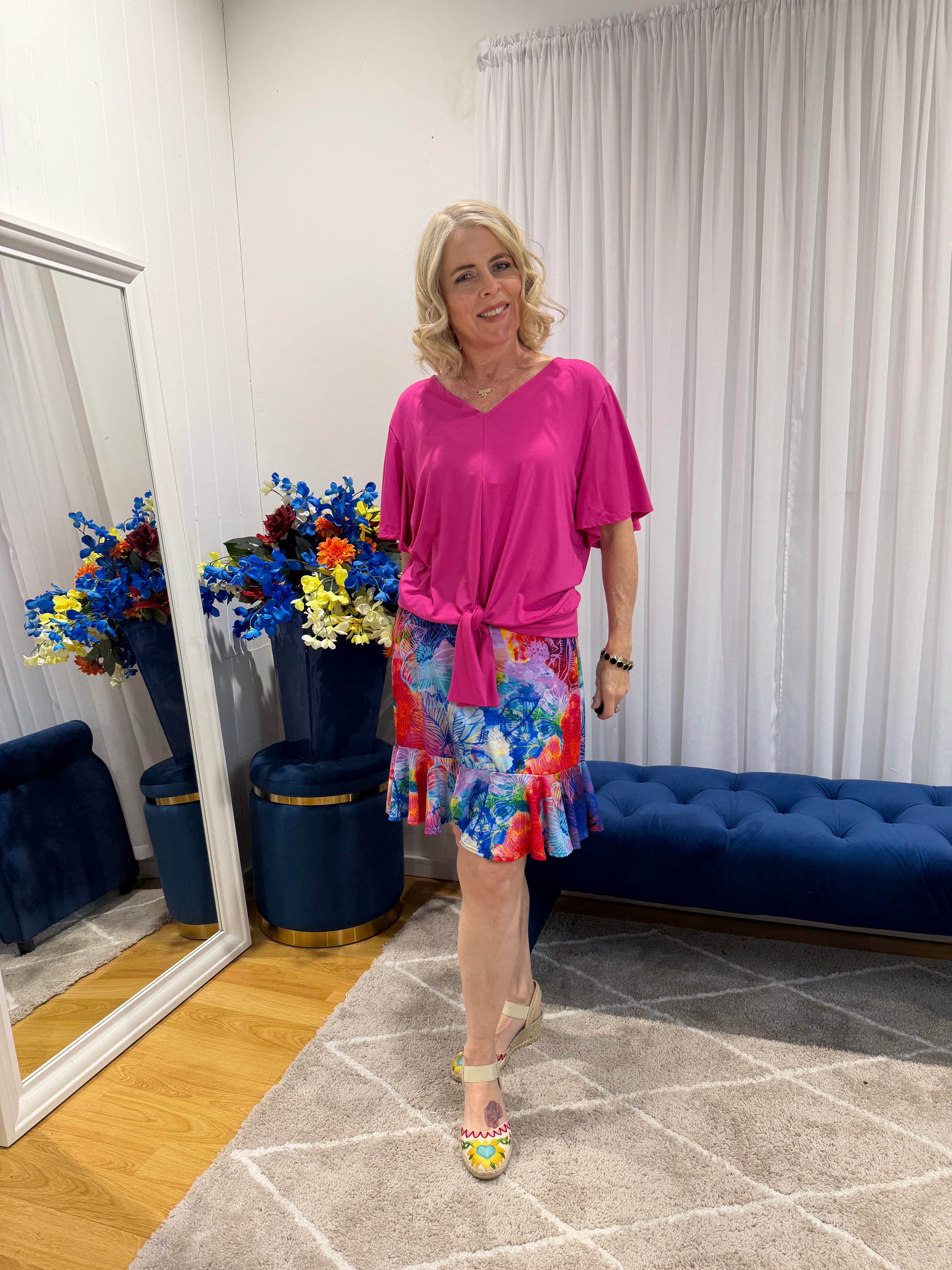 Woman wearing pink top and short colourful skirt 