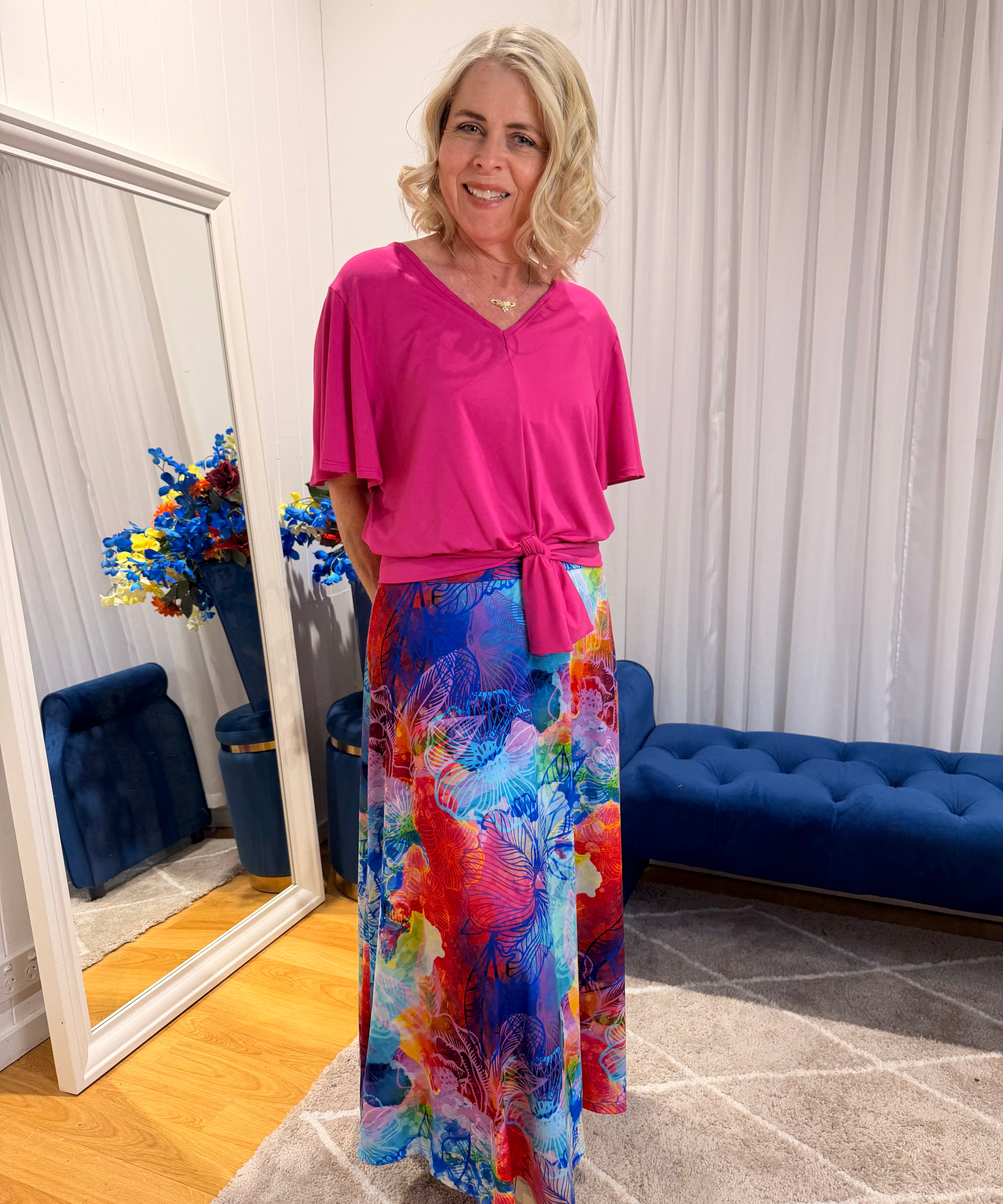 Woman wearing pink short sleeve top and colourful skirt.