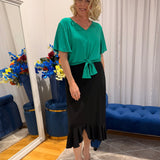 Woman wearing green top and black skirt