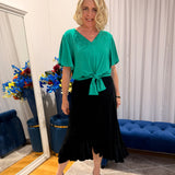 Woman wearing green top and black skirt