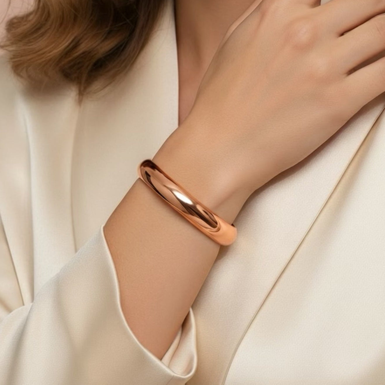 Woman wearing a rose gold bracelet with a neutral background