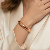 Woman wearing a rose gold bracelet with a neutral background