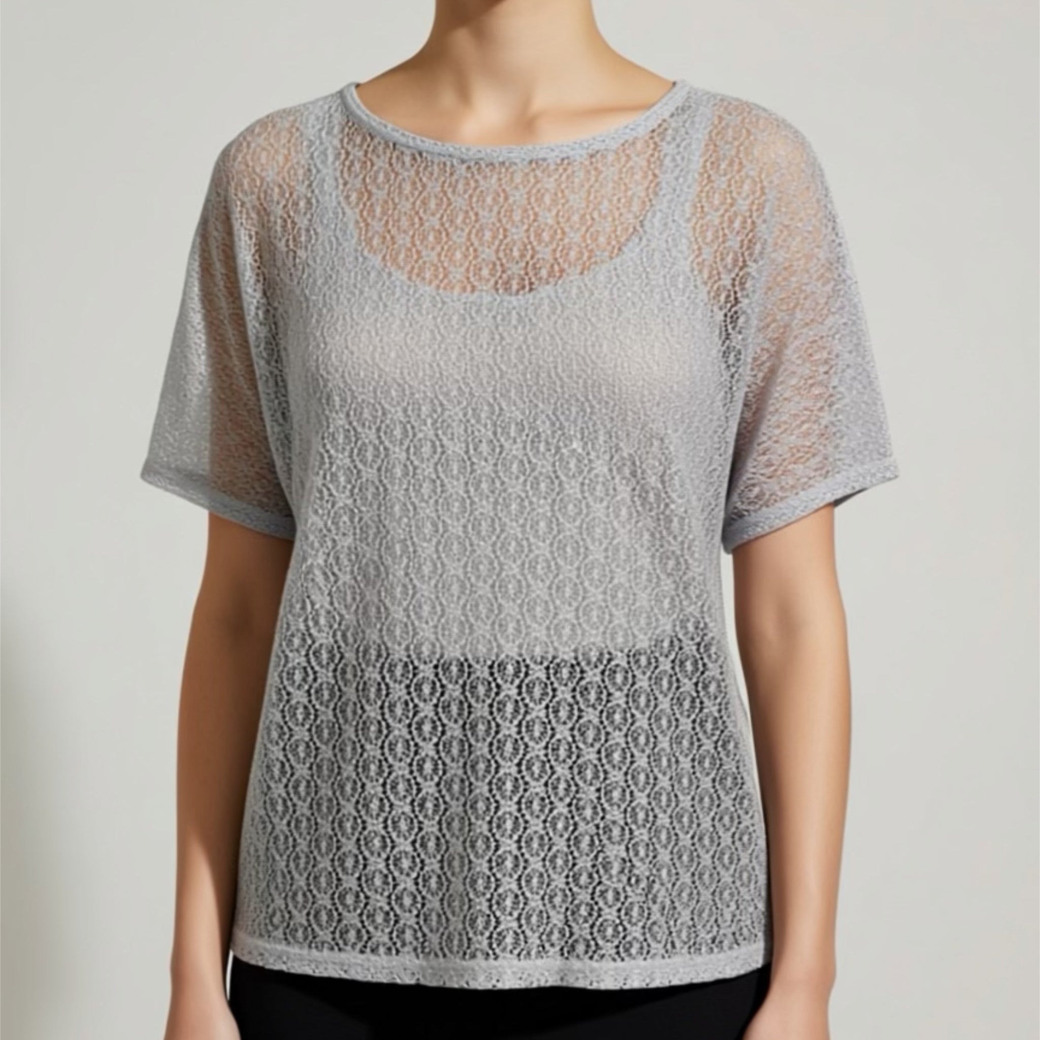 Woman wearing a gray lace top against a plain background