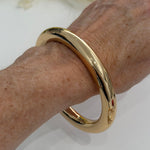 Gold bracelet on a wrist with flowers in the background