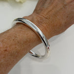 Silver bracelet on a wrist with a white background