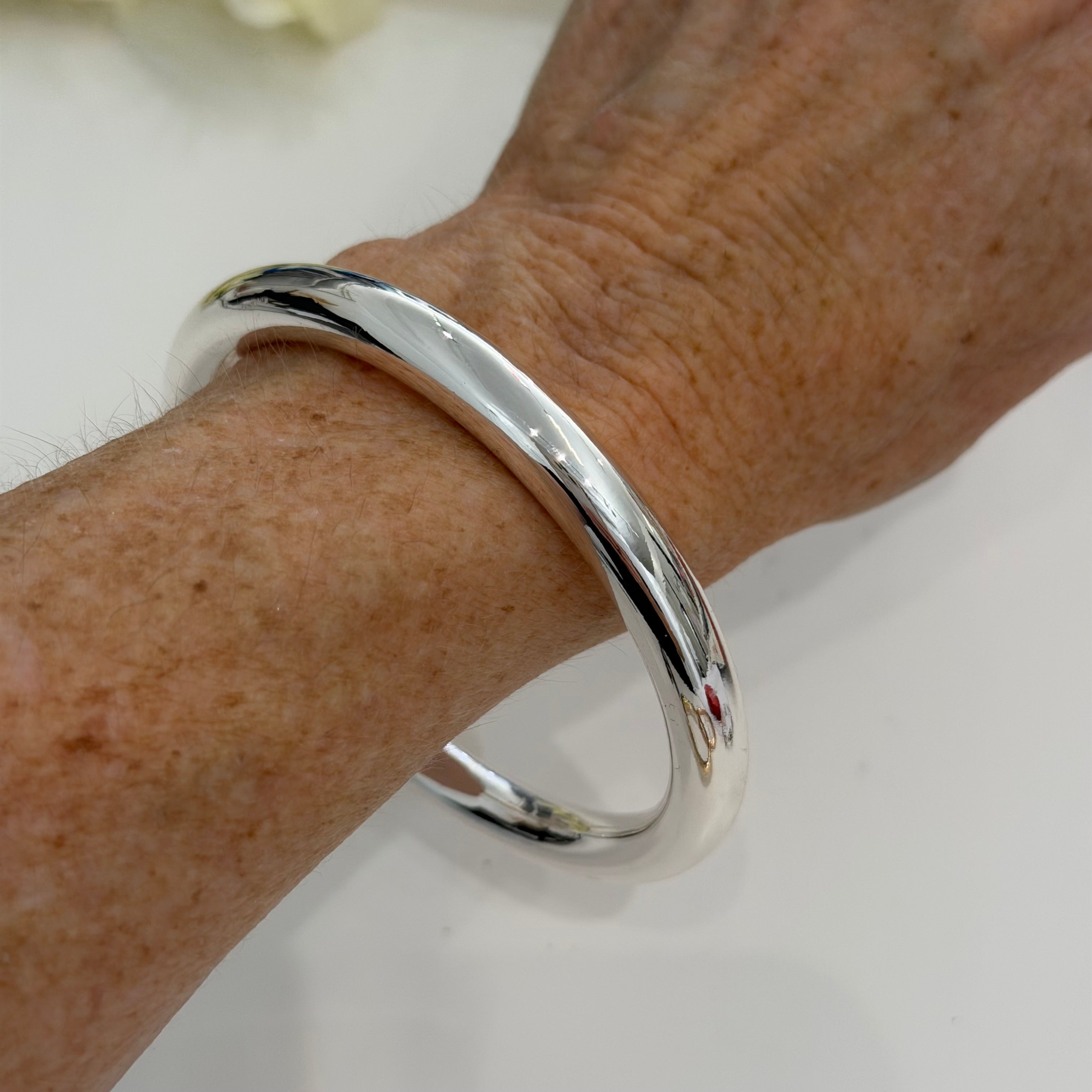 Silver bracelet on a wrist with a white background