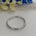 Silver bracelet on a white surface with blurred flowers in the background