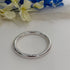 Silver bracelet on a white surface with blurred flowers in the background