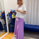 Woman wearing white top and purple skirt 
