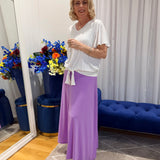 Woman wearing white top and purple skirt 