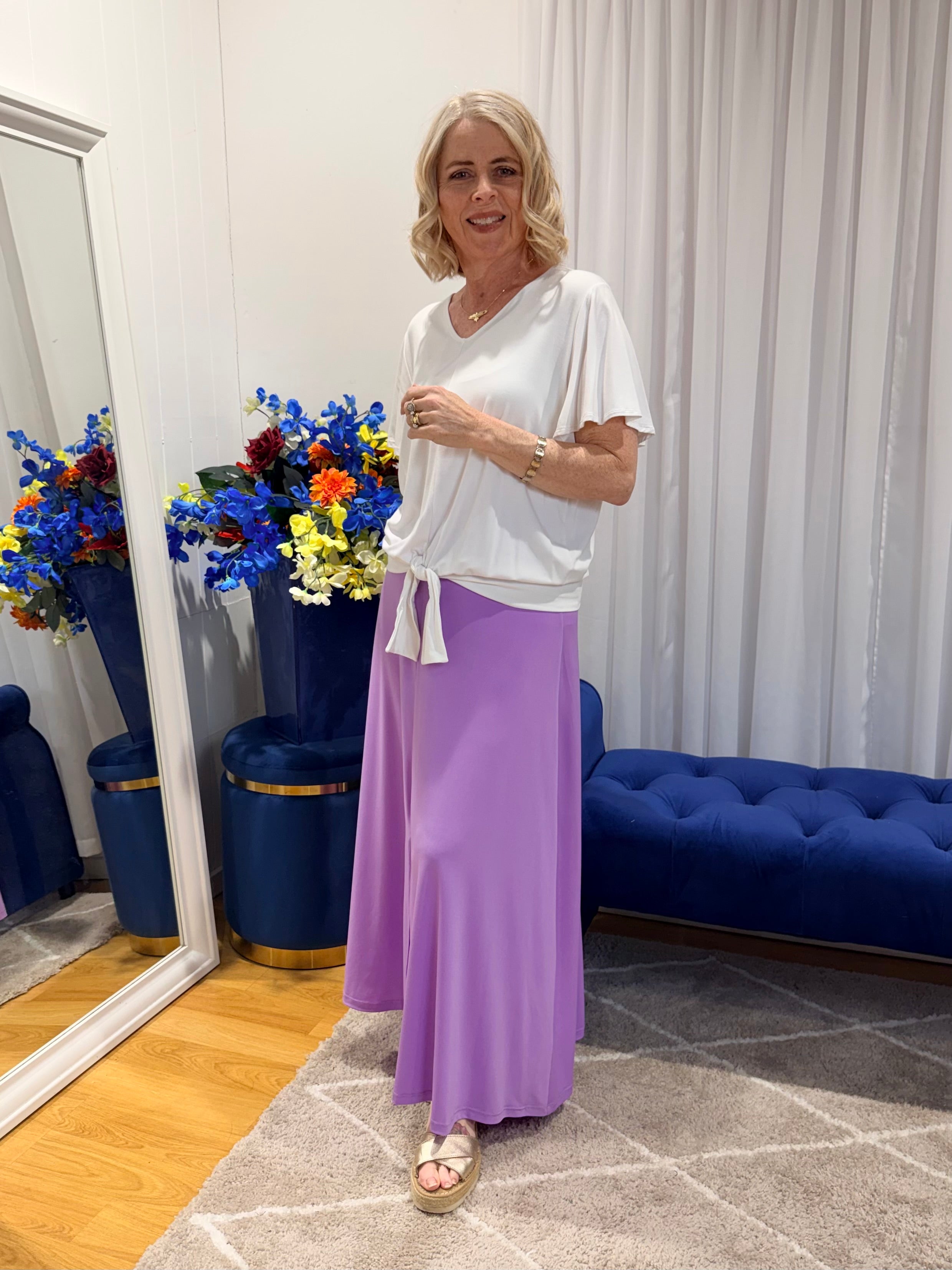 Woman wearing white top and purple skirt 