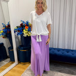 Woman wearing white top and purple skirt 