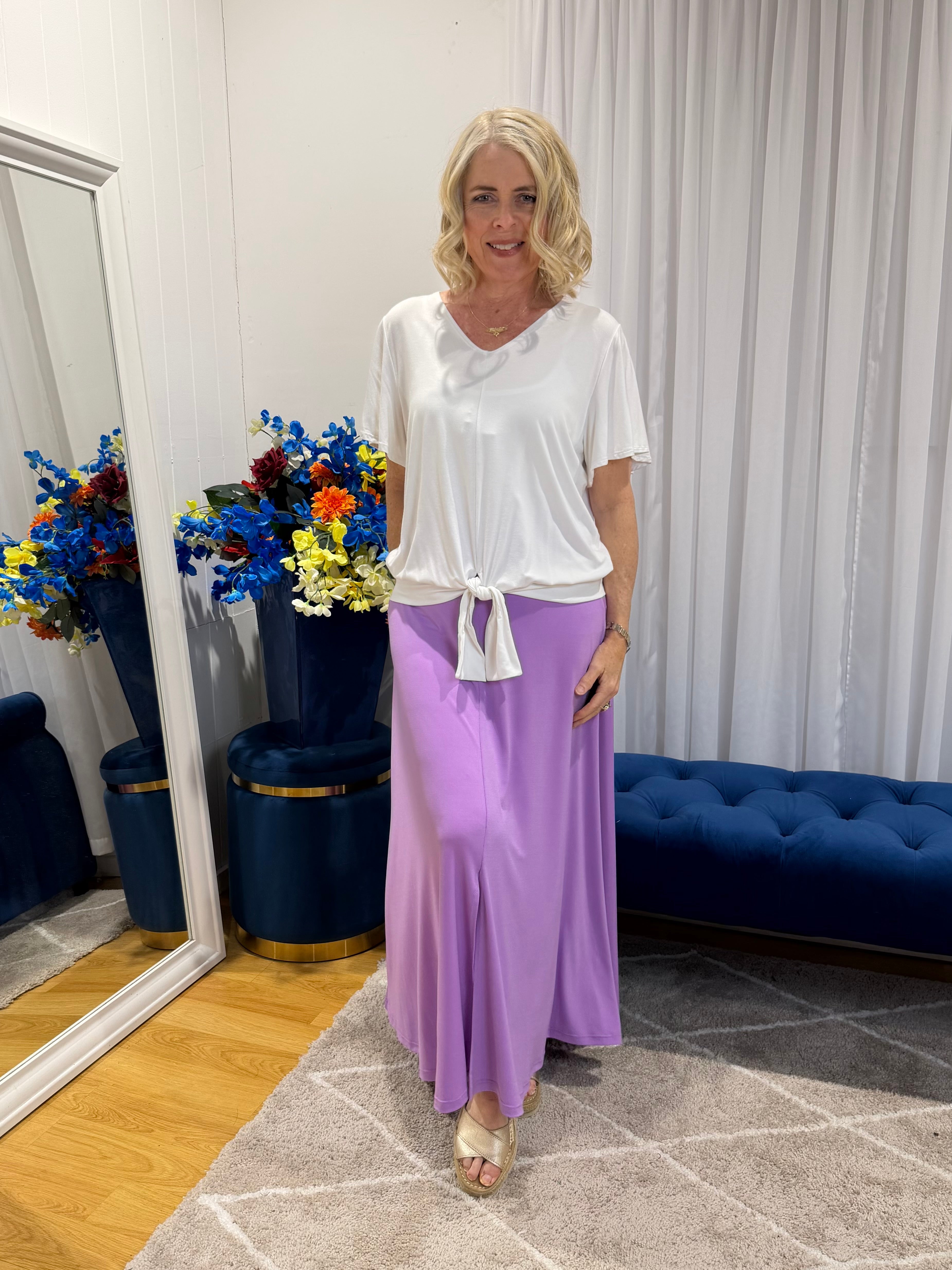 Woman wearing white top and purple skirt 