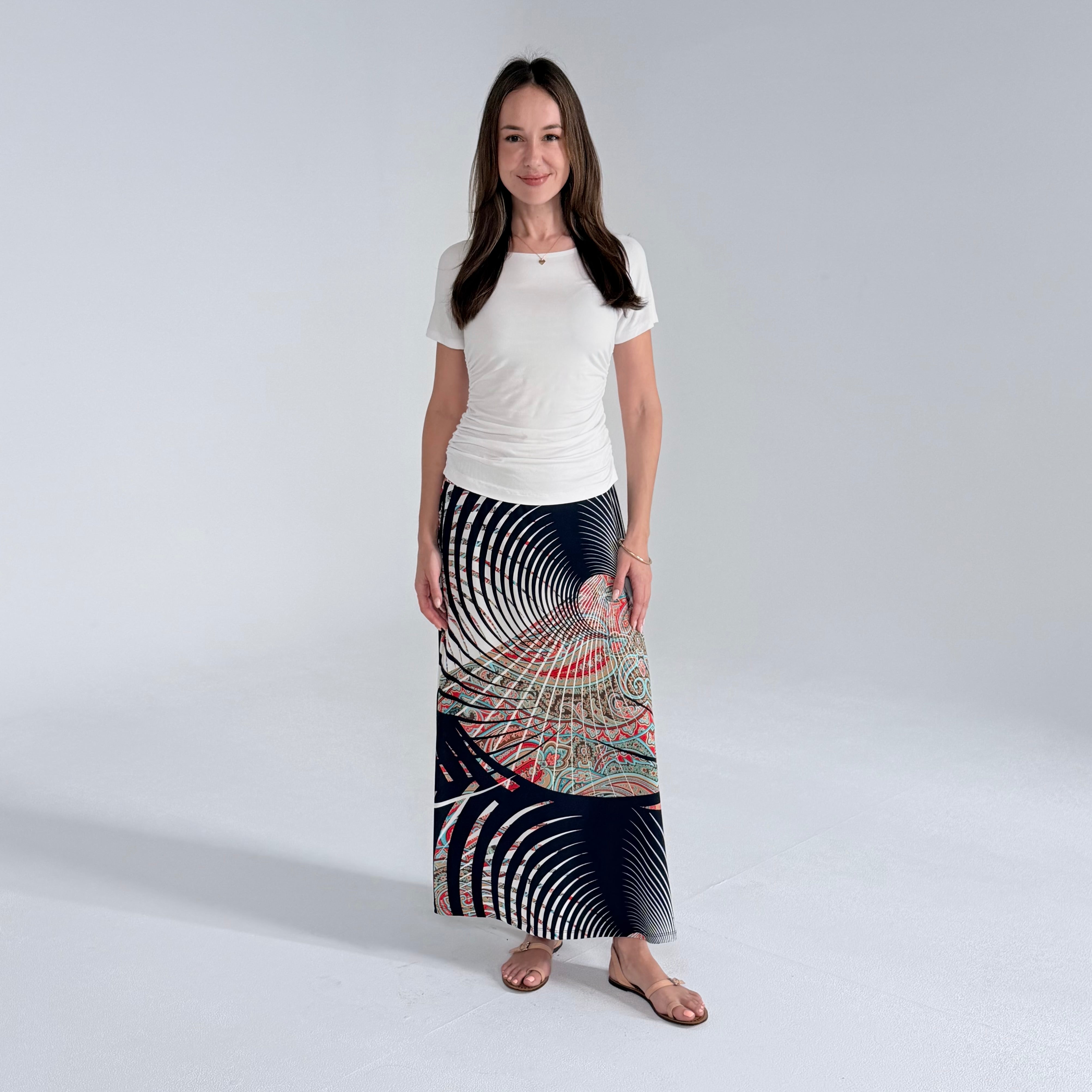 Woman wearing a long, patterned skirt on a plain background