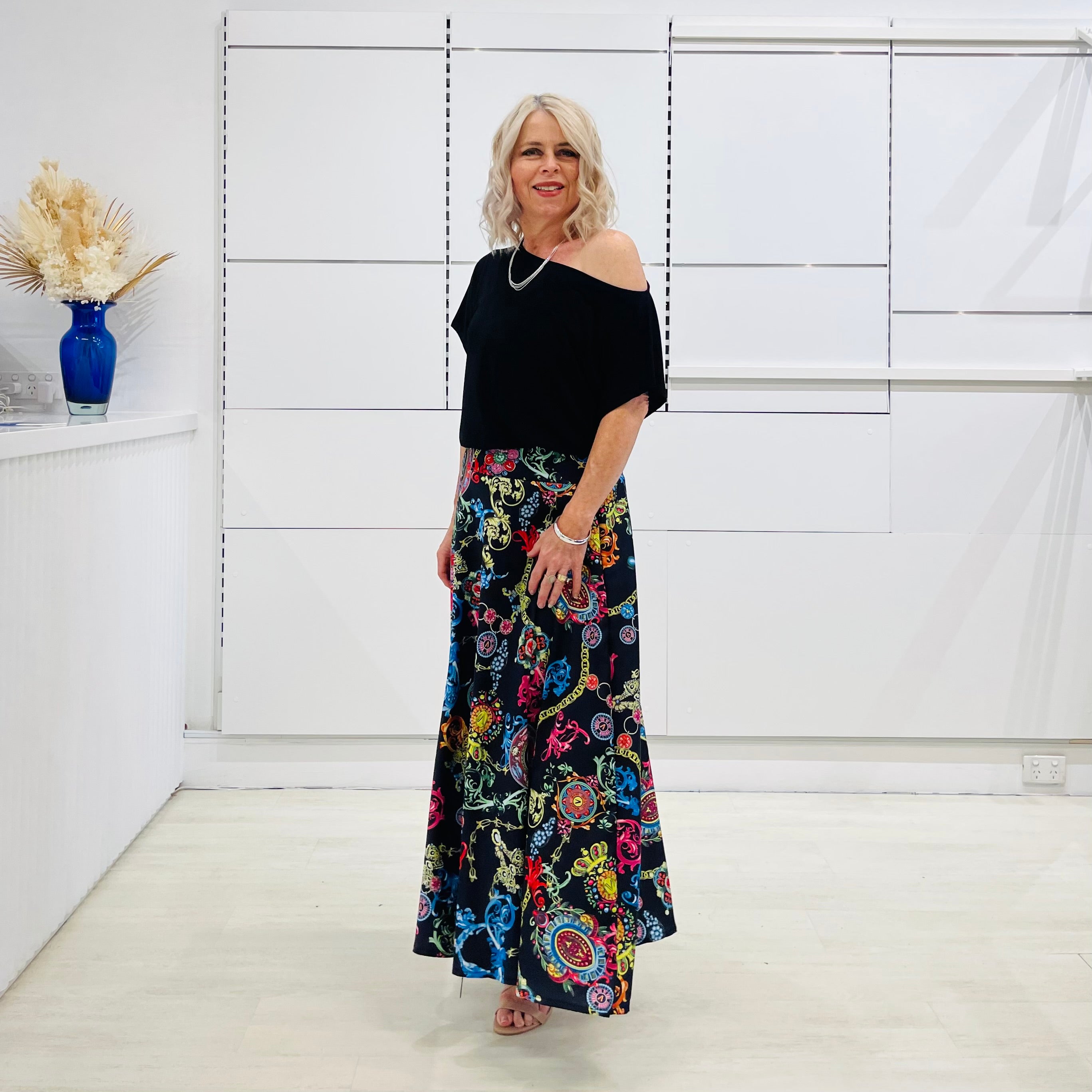 Long, maxi, full circle skirt in multicolored print, flat fitted waistband . Worn with black off the shoulder top.