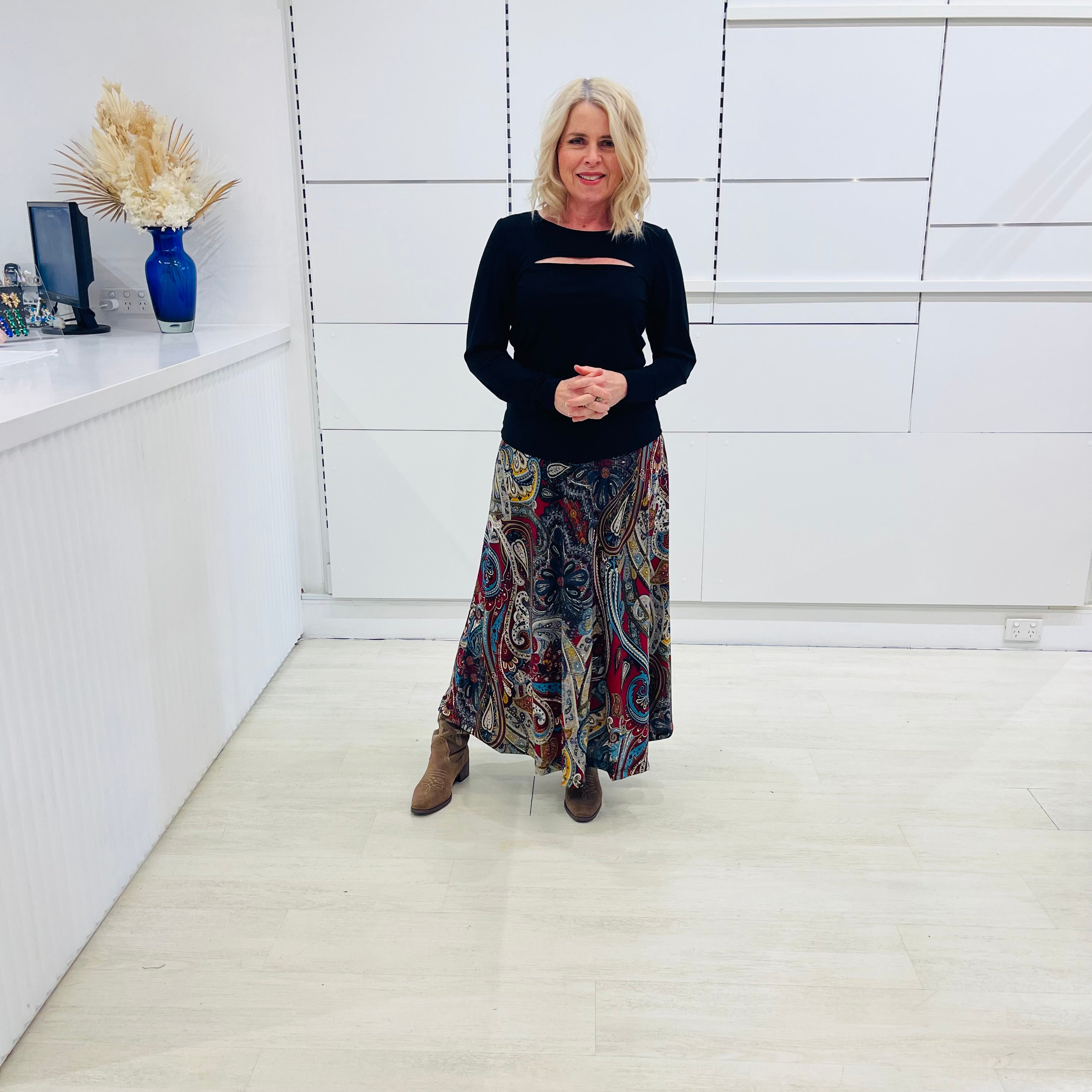 Fashion model  standing in a minimalistic room with white walls and a white floor.
