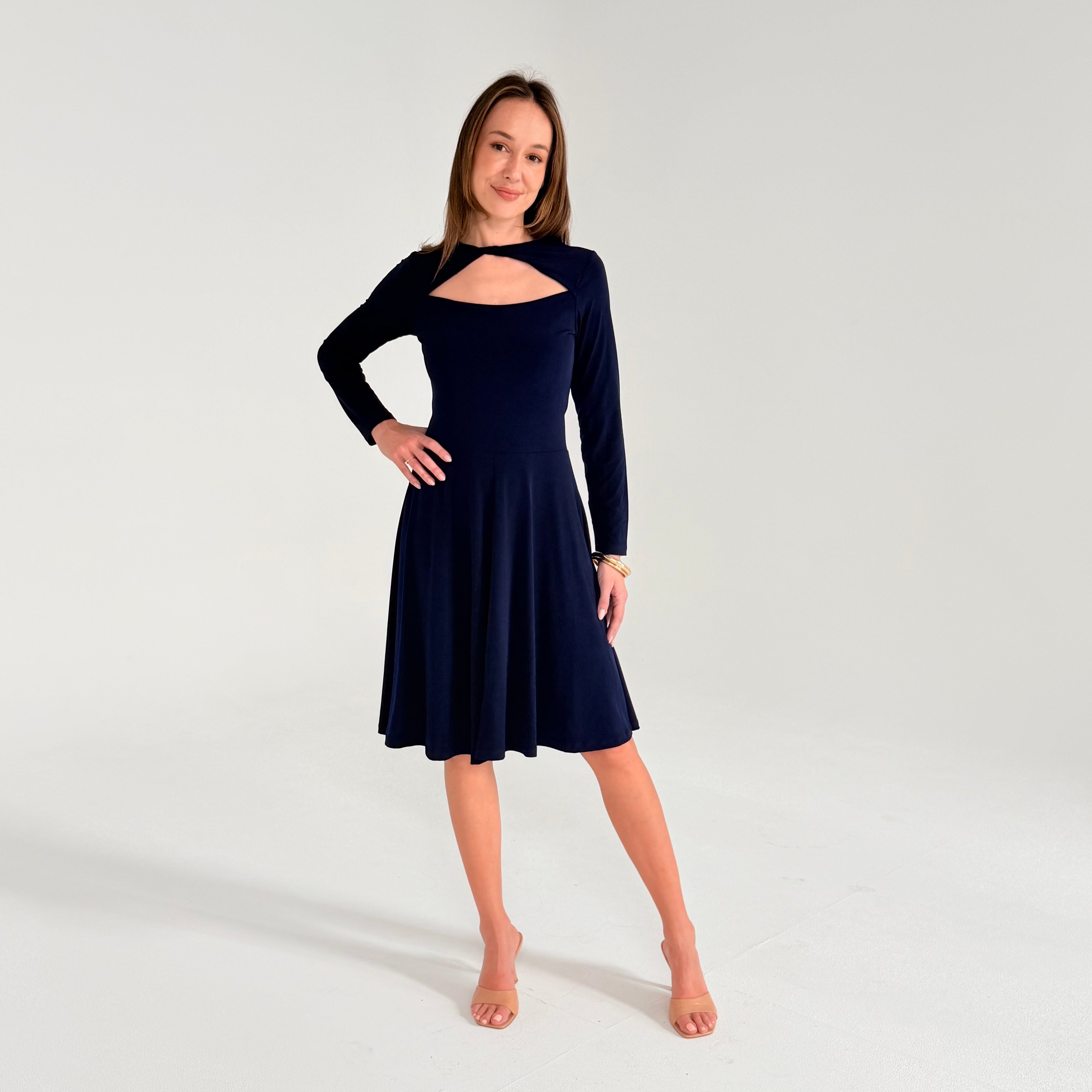 Woman wearing a navy blue dress with long sleeves on a white background
