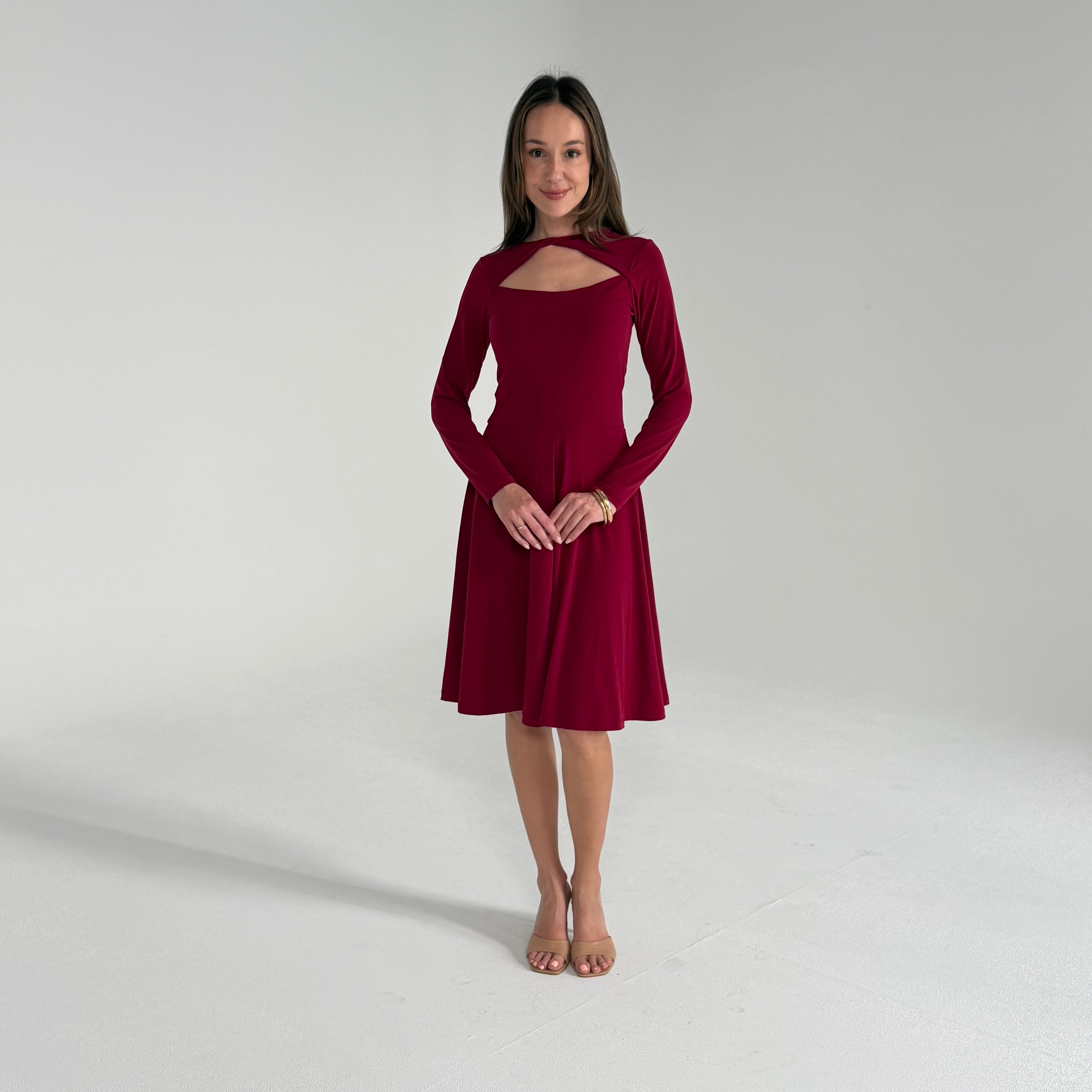 Woman wearing a burgundy dress with long sleeves on a light gray background