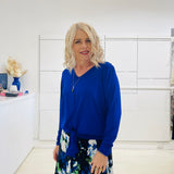 Relaxed fit, cobalt blue bamboo, v neckline, long sleeve, tie front detail, dressy top. Worn with midi length skirt with blue, black, white pattern print.