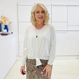 White long sleeve, v neckline, top with waist tie front, worn with floral, midi length skirt.
