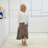 White long sleeve, v neckline, top with waist tie front, worn with floral, midi length skirt.