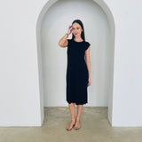 Woman wearing a black dress standing in a white archway.