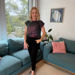 Woman standing in a living room with blue sofas and a window view.