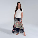 Woman wearing a long, patterned skirt with a white top on a plain background