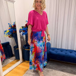 Woman wearing pink short sleeve top and colourful skirt.