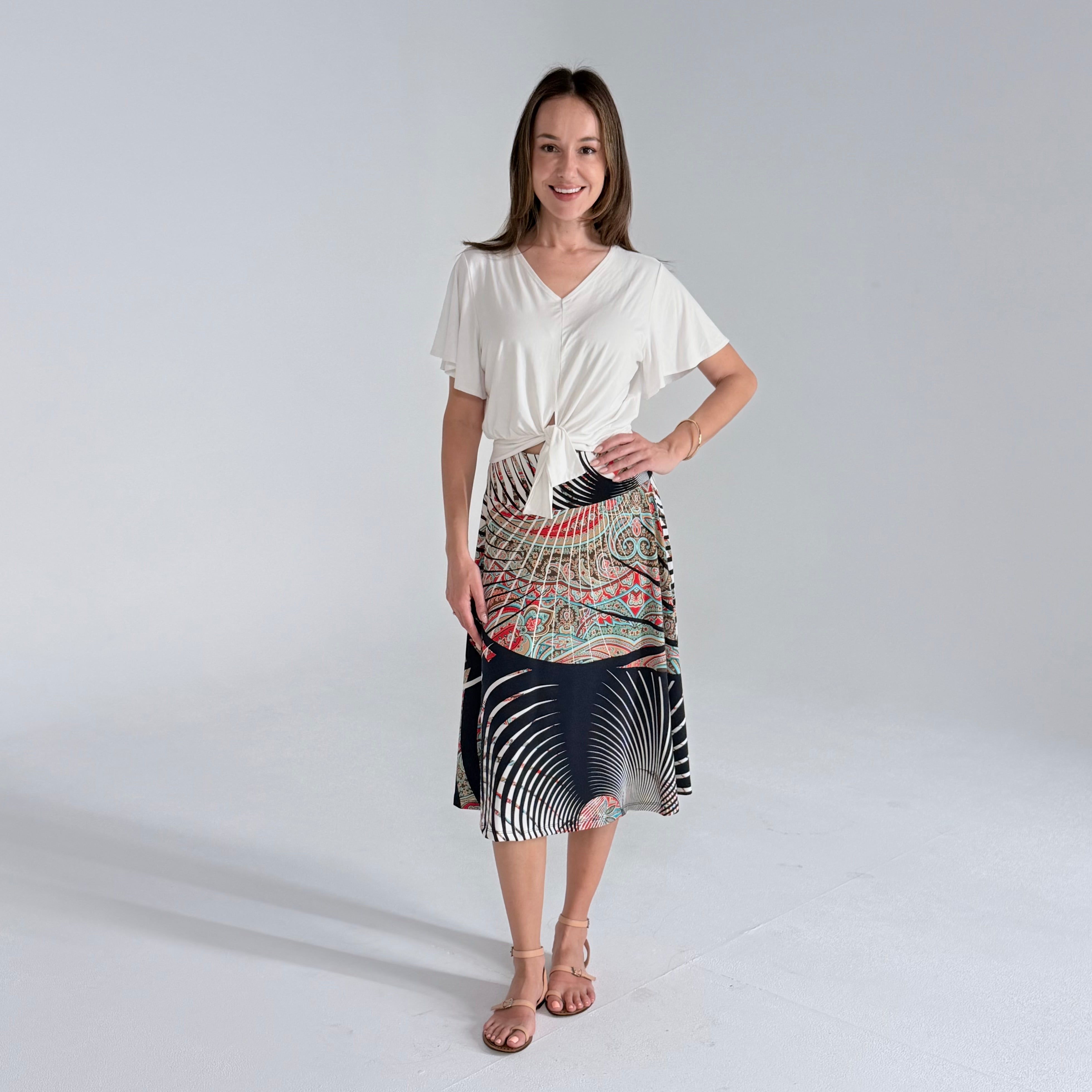 Woman wearing a white top and patterned skirt on a plain background