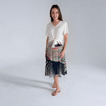 Woman wearing a white top and patterned skirt on a plain background