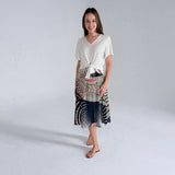 Woman wearing a white top and patterned skirt on a plain background