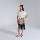 Woman wearing a white top and patterned skirt on a plain background