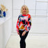 Woman wearing a colorful sweater in a minimalistic room.
