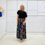 Long, maxi, full circle skirt in multicolored print, flat fitted waistband . Worn with black off the shoulder top.