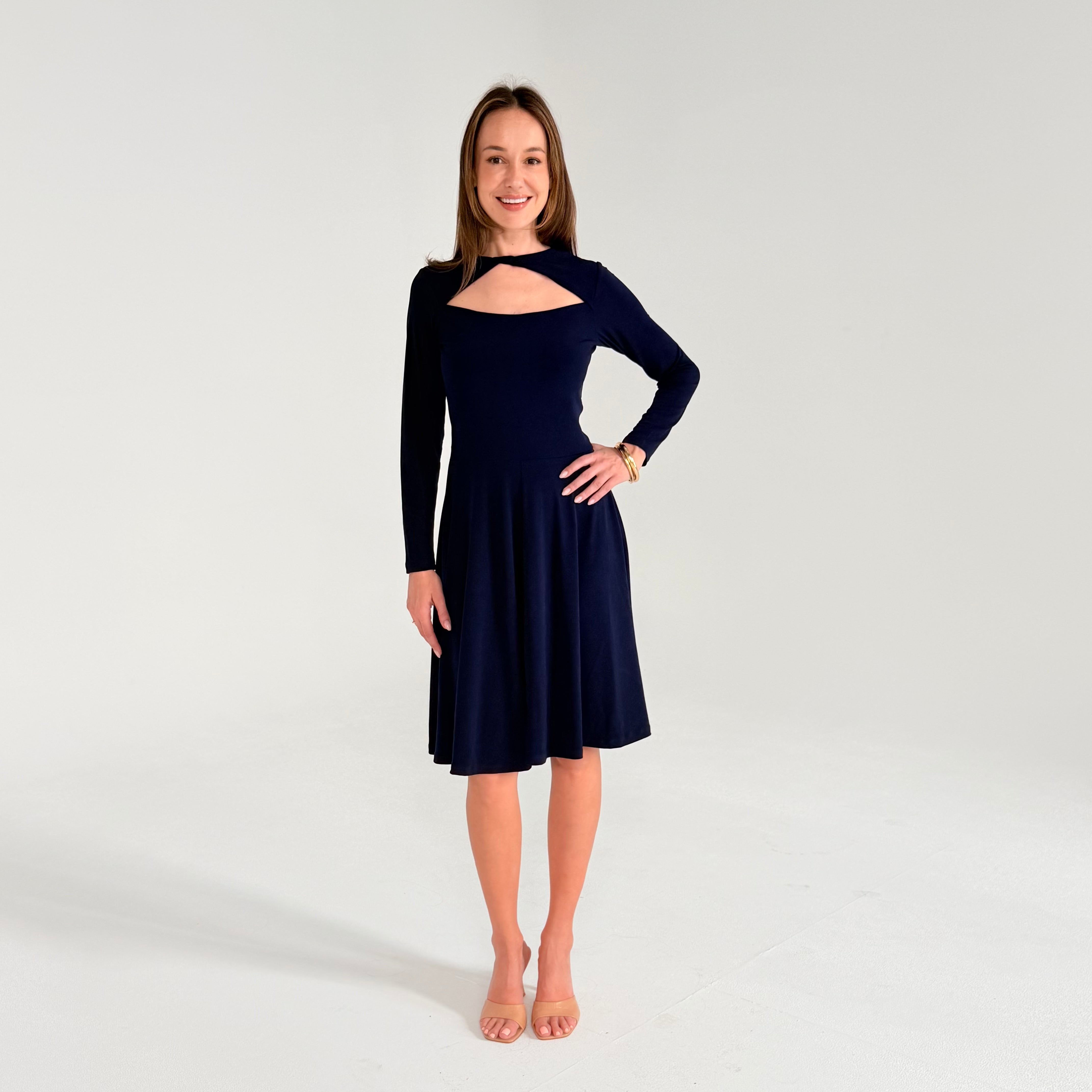 Woman wearing a navy blue dress with cut-out details on a white background